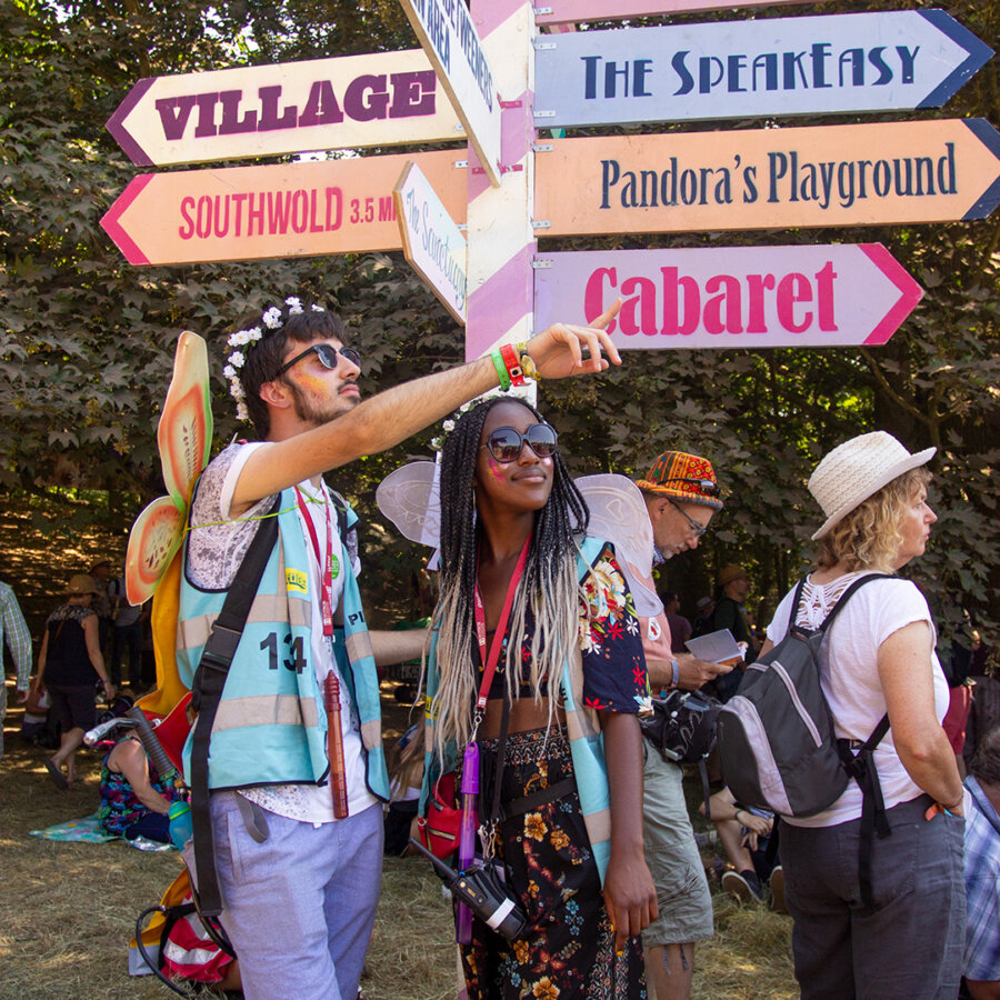 two pixie volunteers standing in front of the latitude sign post. 