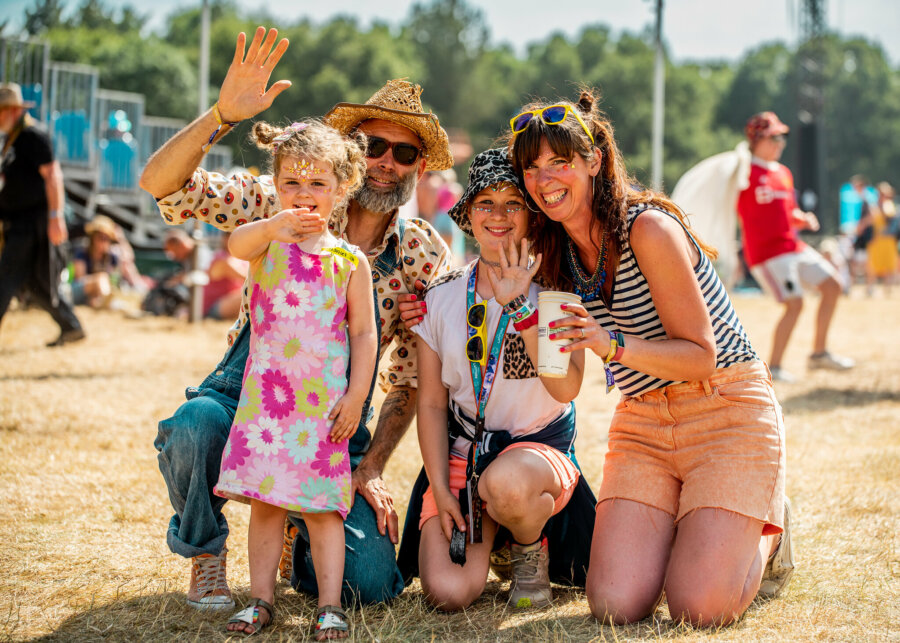 a family with a young child smiling and waving at the camera