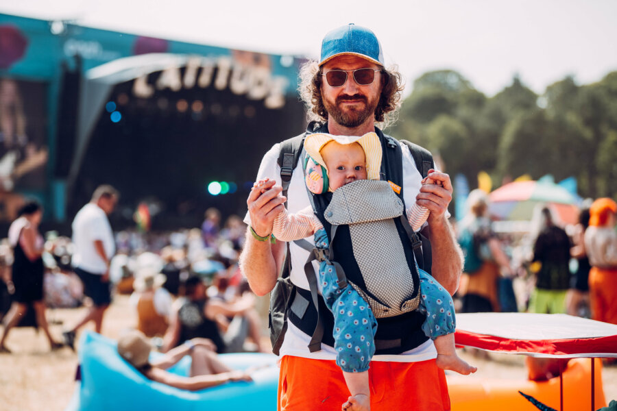 a father and a baby in front of the obelisk area. the baby is wearing ear defenders.