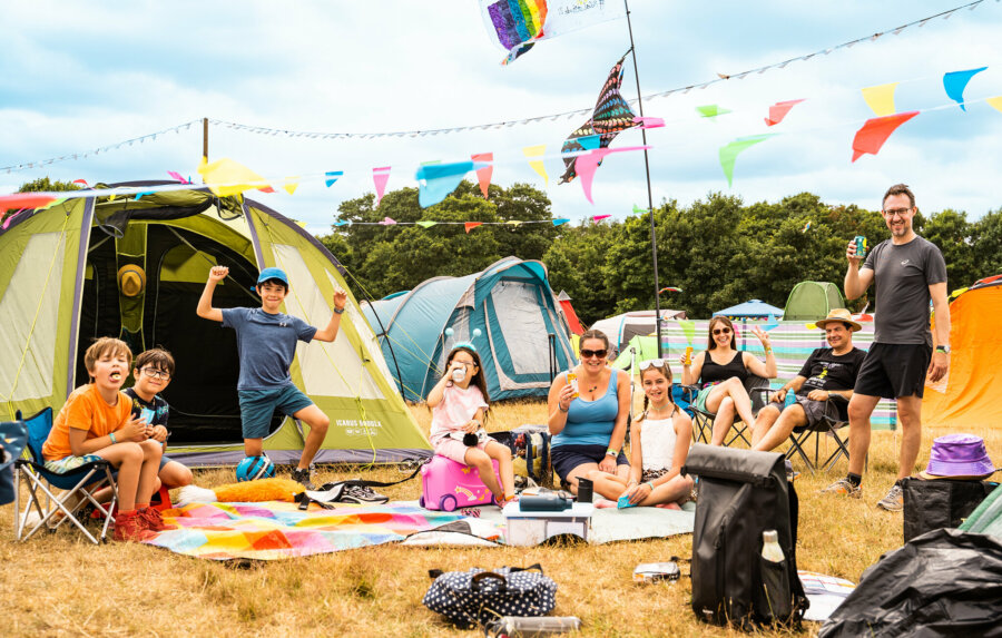 a family set up in the campsite, with tents, blankets and bunting. 