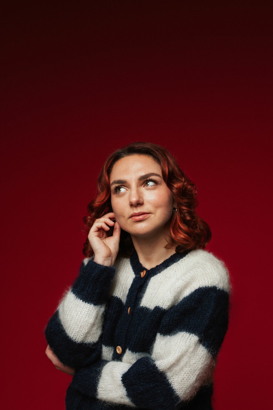 Ania Magliano wearing a black and white cardigan stood against a red background