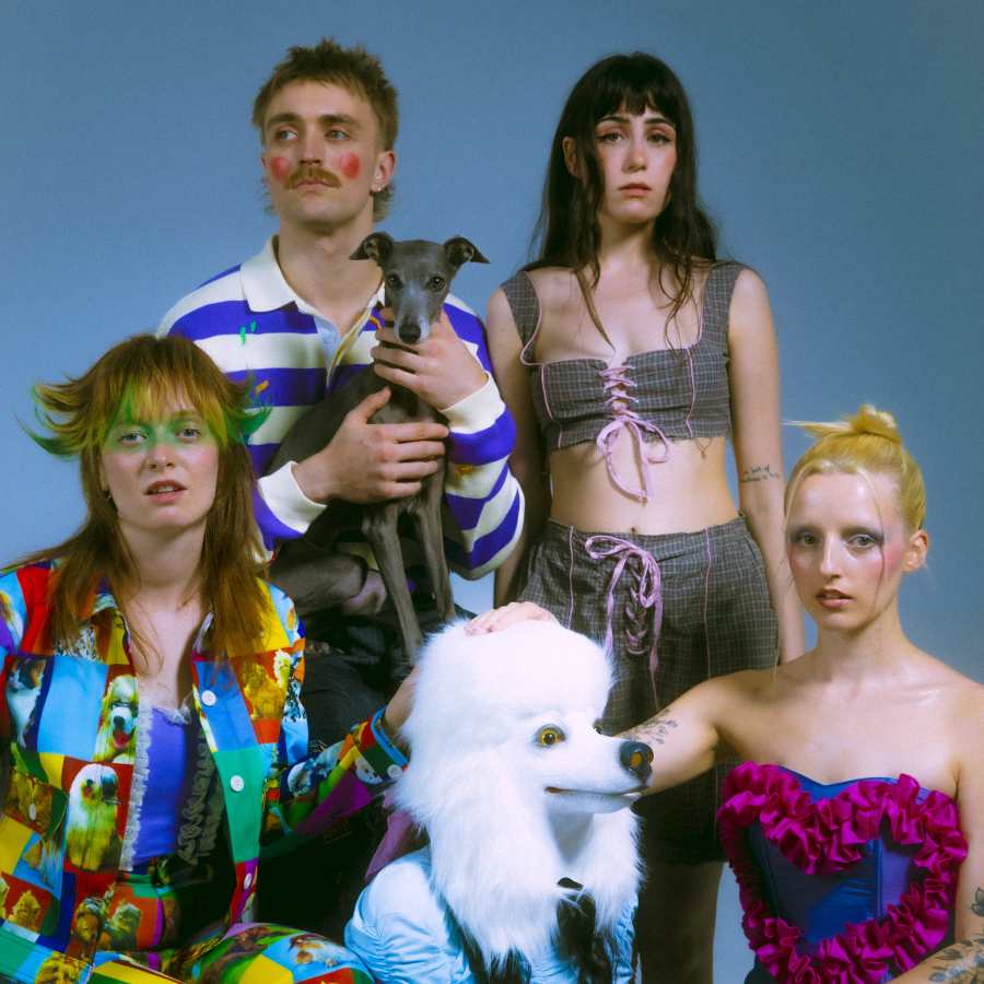 the band FIZZ (L-R: Orla Gartland, Martin Luke Brown, Dodie, Greta Isaac) posing with a fake white poodle.
