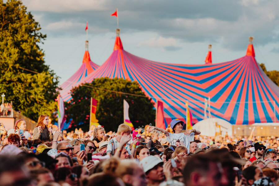 image of crowd at latitude in front of red and blue striped tent