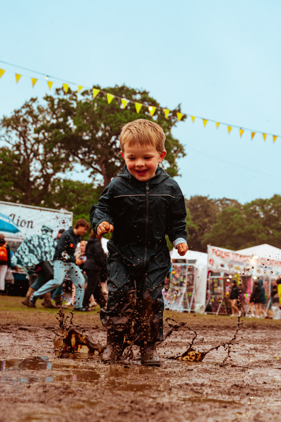small child jumping in muddy puddle