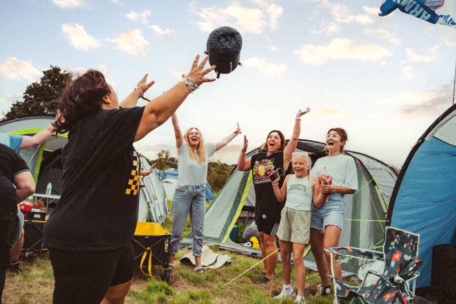 punters in the campsite throwing a sleeping bag in the air